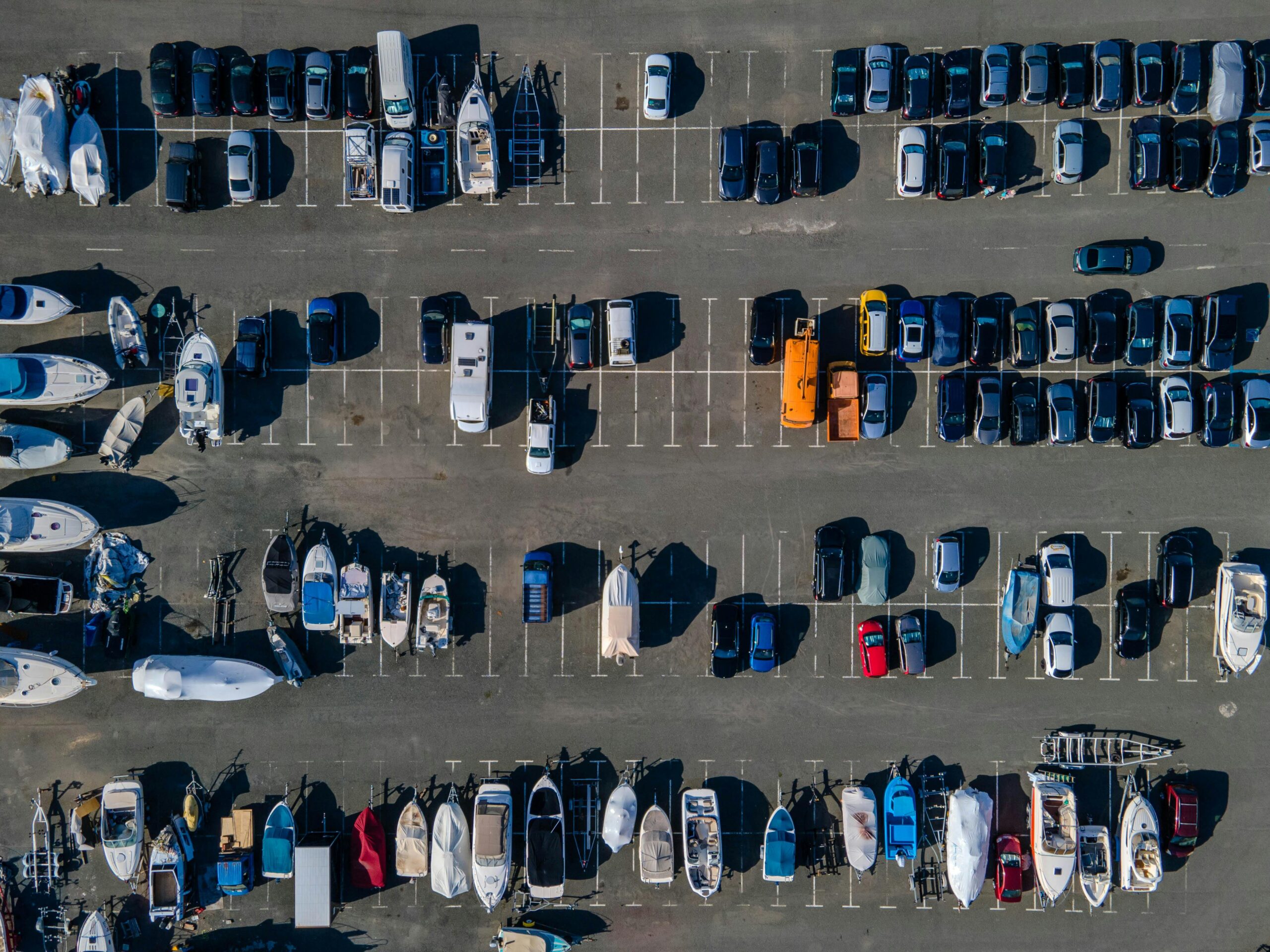 Aerial view showcasing parked boats and cars in a sunny lot. Ideal for transport themes.